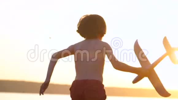 一个带着飞机的男孩沿着海岸跑视频的预览图