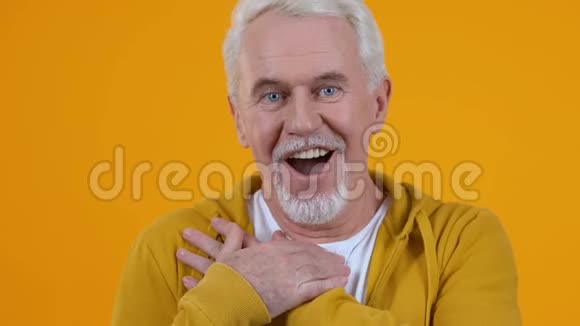善良的男性养老金领取者欣赏橙色背景带着爱看好消息视频的预览图