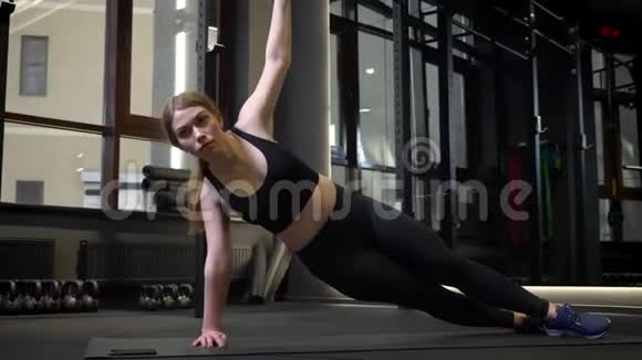 年轻的集中运动女孩站在旁边的木板上她的手臂在健身房里张开视频的预览图