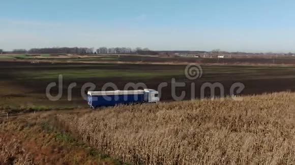 一辆卡车在美丽乡村的道路上的空中射击卡车在玉米地背景的土路上行驶半半半视频的预览图