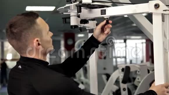 男子手在模拟器上减轻重量引脚选择换板重量堆叠体育运动视频的预览图