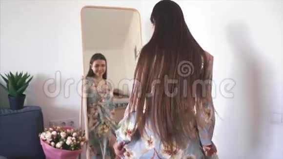 年轻快乐的女人试着在镜子前穿新衣服视频的预览图