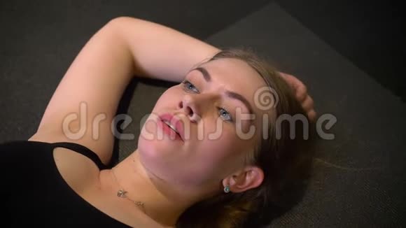 躺在卡里马特上的汗流浃背和疲惫的运动女孩在健身房里疲惫和疲惫的特写照片视频的预览图