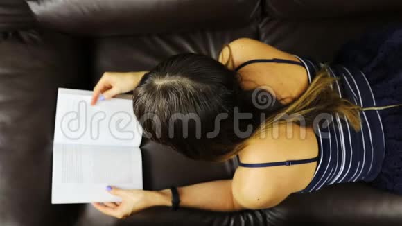 一个穿着条纹连衣裙的女孩在肚子上读一本书从上面看视频的预览图