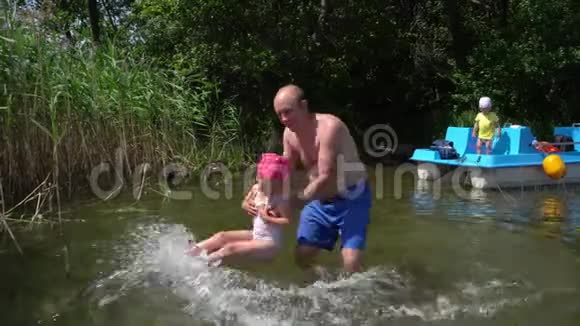 爸爸和女儿在水里玩儿子站在双体船上万向节运动视频的预览图
