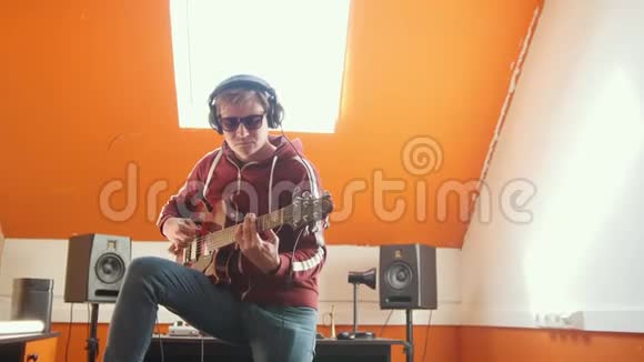 一个戴着耳机的男人在明亮的录音室弹吉他视频的预览图