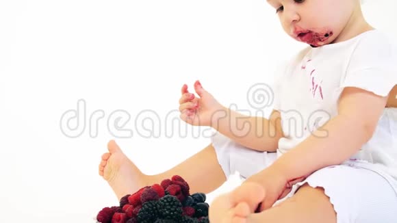有趣的女婴在白色背景下吃浆果视频的预览图