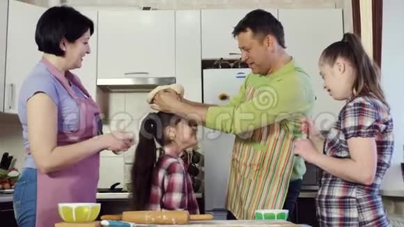 父亲在厨房里和家人开玩笑一边用面团煮食物视频的预览图