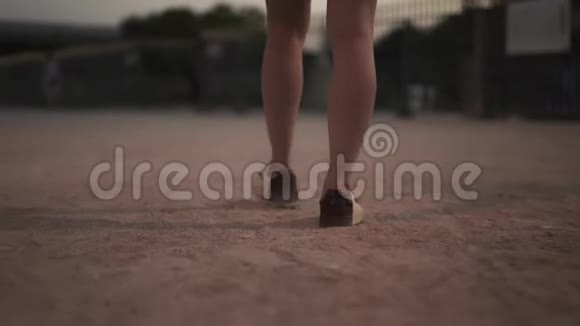 穿着靴子的年轻女子光着腿向公园门口走去视频的预览图