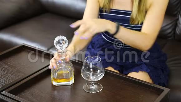 一个女孩把瓶子里的酒精倒入玻璃杯里视频的预览图