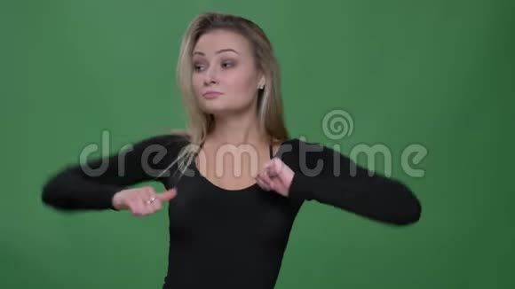 一幅穿着黑色衬衫的女商人在绿色背景下快乐而奇怪地跳舞的肖像视频的预览图