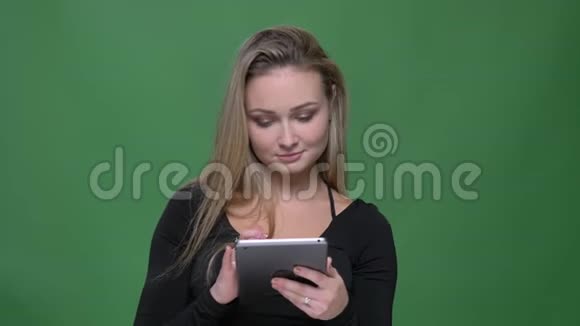 穿着黑色衬衫的女商人看着平板电脑绿色背景下露出积极的微笑视频的预览图