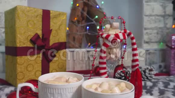 两个带有可可和棉花糖的杯子放在年轻女孩的圣诞餐桌上视频的预览图