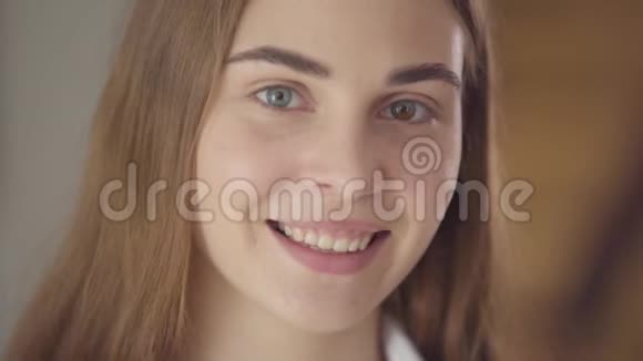 早晨美丽的年轻微笑的女人用不同的彩色眼睛看着相机快乐视频的预览图