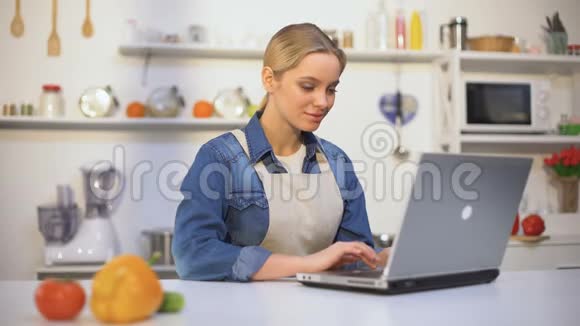 穿围裙的年轻美女在网上博客上搜索食物配方视频的预览图