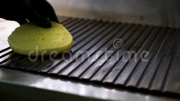 特写厨师手把汉堡包放在热烤架上用黄油涂上油脂视频的预览图