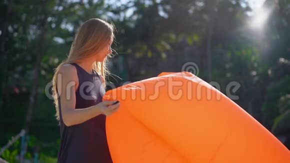 一位年轻女子在热带海滩上充气沙发上的超慢镜头暑假概念视频的预览图