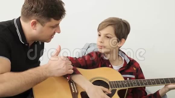 男孩花了很大的时间学习如何和他的父亲玩吉他慢动作视频的预览图