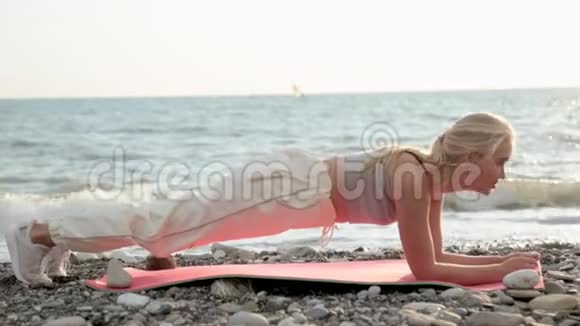健身海滩女人微笑着做瑜伽练习快乐女孩训练腹肌锻炼核心肌肉视频的预览图