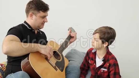 父亲和儿子慢动作演奏吉他的教育过程视频的预览图