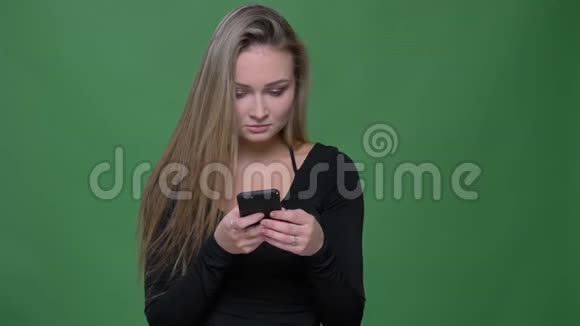 穿着黑色衬衫的女商人专心看着智能手机在绿色背景下调整头发视频的预览图
