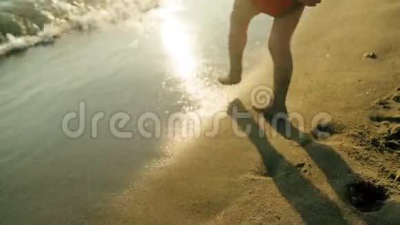 在夕阳西下的夏日里孩子们赤着脚在沙滩上奔跑视频的预览图
