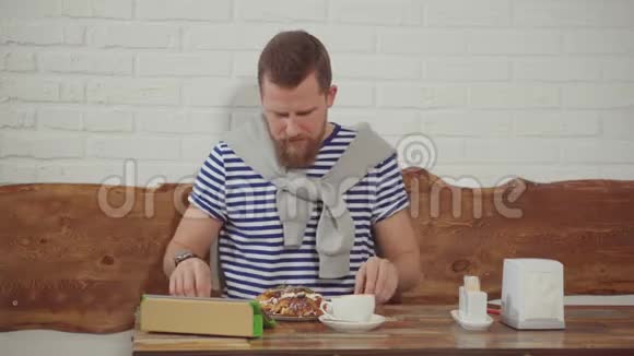 男人在咖啡馆打平板电脑在咖啡中吃甜点视频的预览图