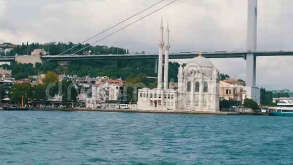 住宅区背景的美丽白色清真寺从大海和旅游船经过的景色伊斯坦布尔视频的预览图