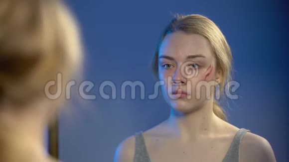 哭泣的年轻女子对着镜子消毒脸部伤口绝望的问题视频的预览图