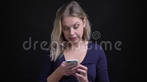 金发女商人穿着蓝色衬衫工作智能手机手表进入相机对黑色背景感到惊讶视频的预览图