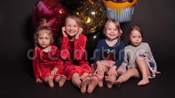 孩子们坐在地板上身后放着五颜六色的气球视频的预览图