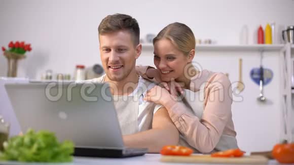 年轻夫妇在网站上寻找食物食谱笑着厨房新手视频的预览图
