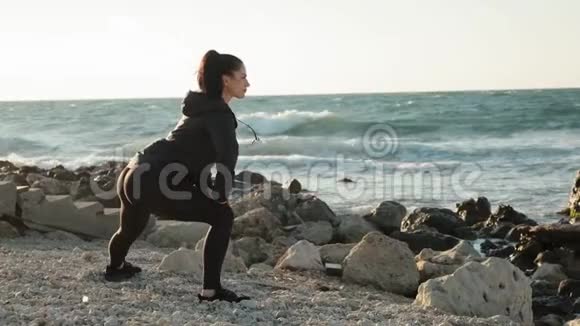 年轻的运动女子在海边的日出上做侧击动作视频的预览图