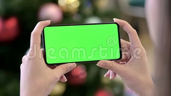 在圣诞装饰附近保持水平色度键屏智能手机视频的预览图