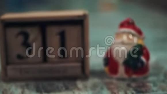 12月31日在带有立方体的圣诞老人身影上在背景中闪烁着模糊的灯光的桌子上相机的通量视频的预览图