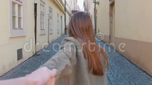 一个年轻的微笑的女人牵着她的男朋友手扔街视频的预览图