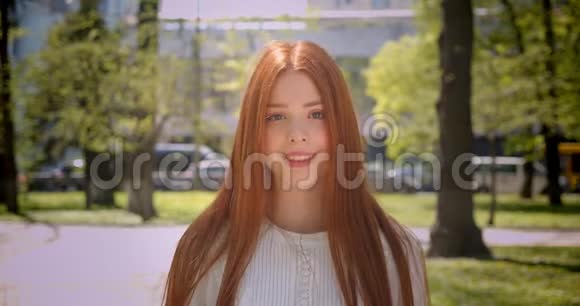 红发女孩走进镜头高兴地微笑着走进绿色公园视频的预览图