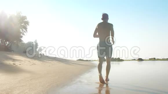 阳光照耀下的强壮运动员沿着海岸线慢跑视频的预览图