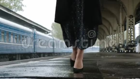 火车站穿着黑色外套的漂亮中年黑发女人下雨了双腿的特写视频的预览图