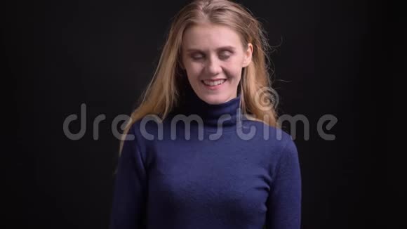 年轻的金发模特穿着蓝色毛衣把她的手指举起来在黑色背景上的镜头中表现出喜欢和尊重视频的预览图