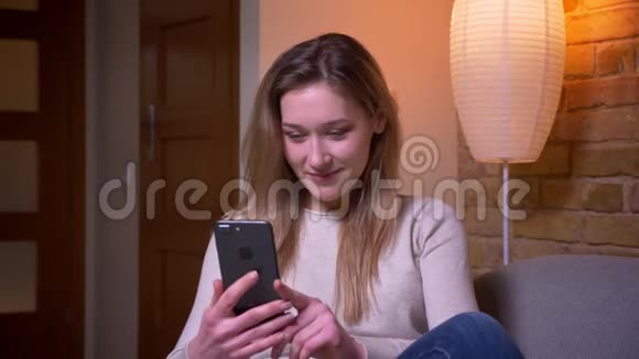 年轻迷人的白种人深色头发的女性用手机特写肖像并用绿色屏幕拍摄视频的预览图