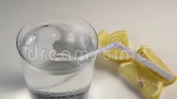 冰块和一根管子在白色背景上的蒸杯中旋转下一片柠檬视频的预览图