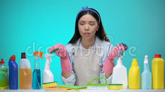 戴手套的家庭主妇拿着海绵对低质量的洗涤剂感到失望视频的预览图