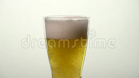 慢动作淡啤酒杯旋转的气泡在泡沫满头下升起视频的预览图