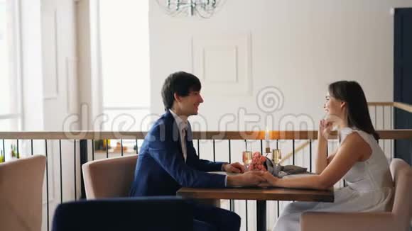 帅哥在约会时和他的女朋友一起坐在桌子上笑着享受浪漫的时刻视频的预览图