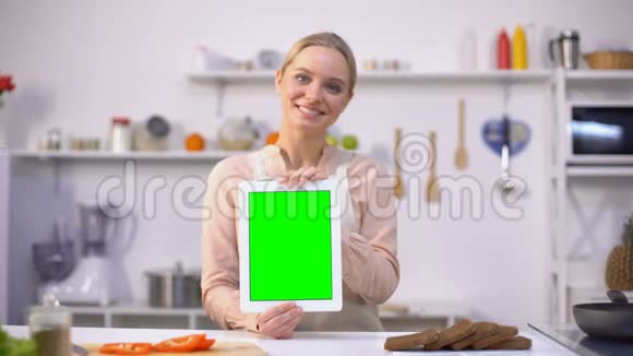 美丽的女孩手持平板电脑绿色屏幕易于烹饪移动应用视频的预览图