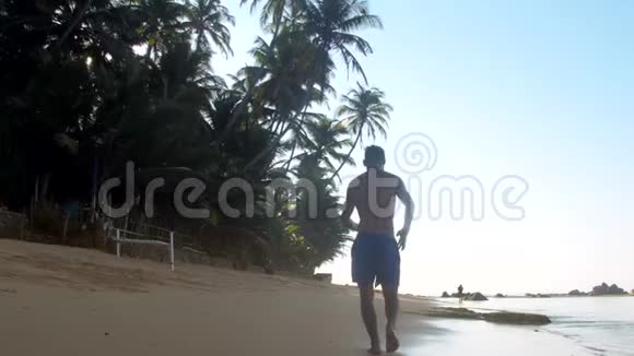 肌肉体操运动员在无尽海洋附近的湿沙上奔跑视频的预览图