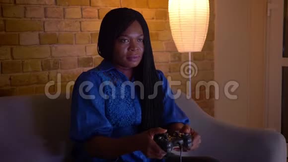 成年非裔美国女性在玩电子游戏坐在沙发上失败的特写镜头视频的预览图