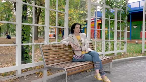 坐在公园长椅上的白人中年黑发女性视频的预览图