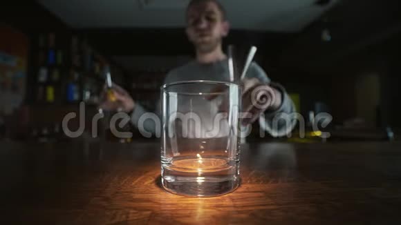 大角度的宏观视频用慢镜头把威士忌倒进玻璃杯在酒吧里倒酒在工作时调酒师4k视频的预览图